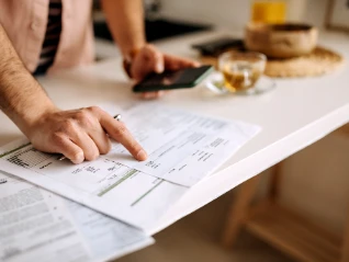 man pointing at sheet and holding mobile phone