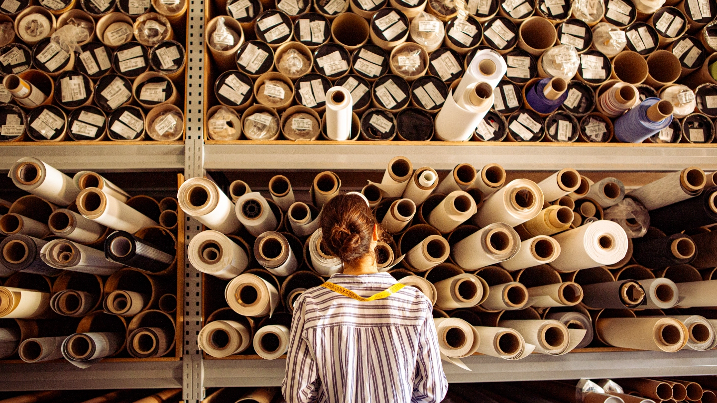 Female textile worker examining reels of fabric
